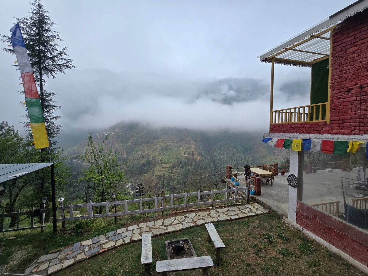 Low cloud over terraced hills, seen from the Glass House lawn with its fire pit and benches near Jibhi
