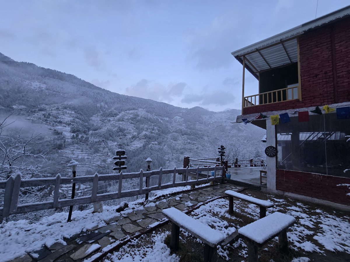 Fresh snow on the lawn, benches and fence beside the Glass House at Peaks N Valley Stays in Chhet near Jibhi, January 2026