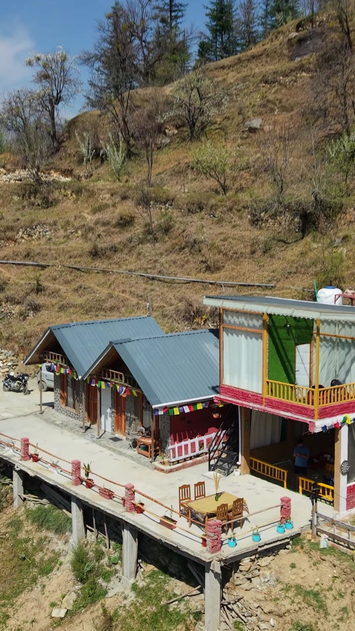 Drone view of the Glass House and Mudhouse cottages on the hillside above the valley in Chhet, near Jibhi